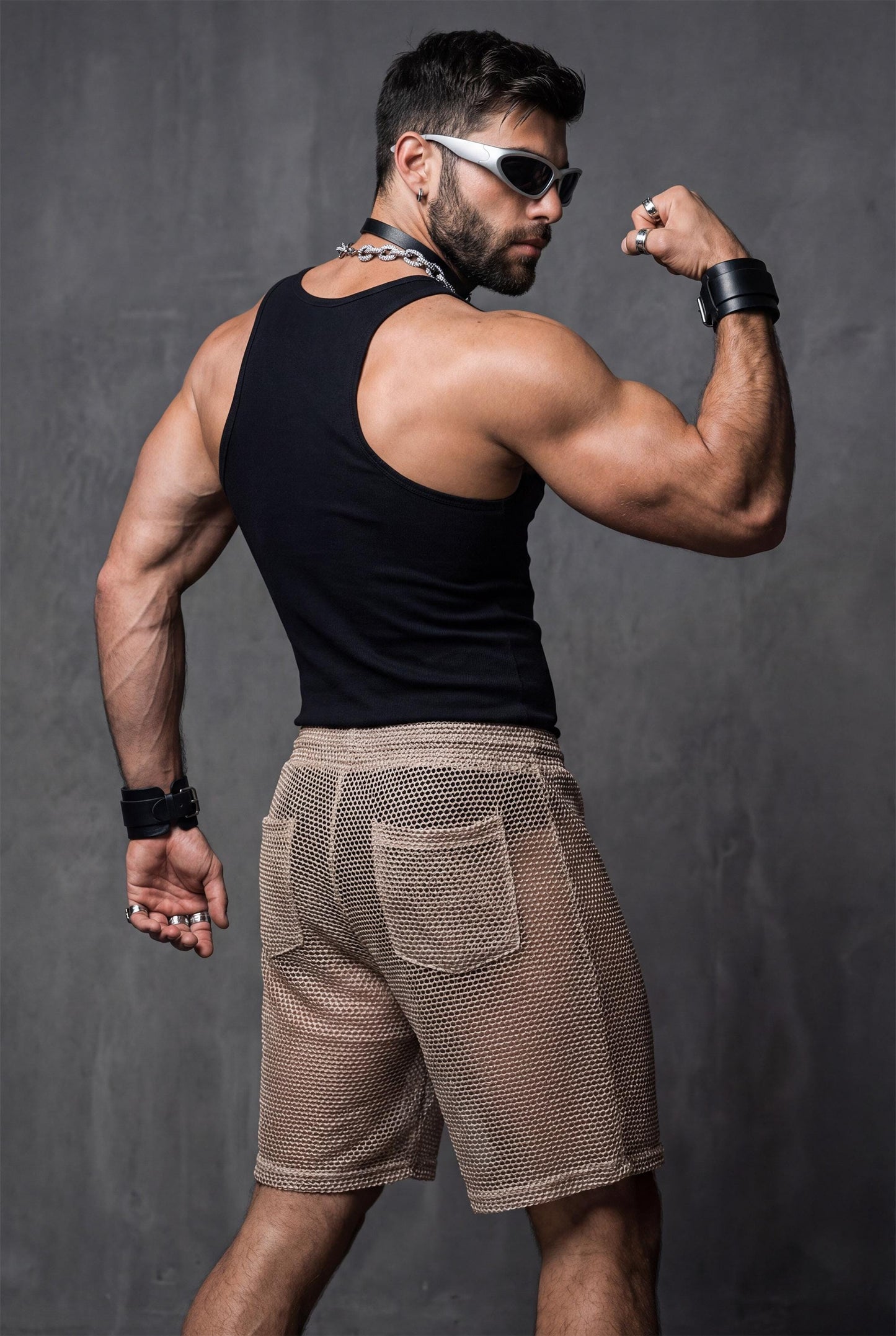 Side profile of see-through mesh shorts on a toned male body. Lightweight mesh follows the legs and highlights muscle definition. Ideal for gay party looks, Berlin underground clubs, raves, and festival wear. Transparent club shorts made for dancing, heat, and high-energy LGBTQ nightlife scenes.