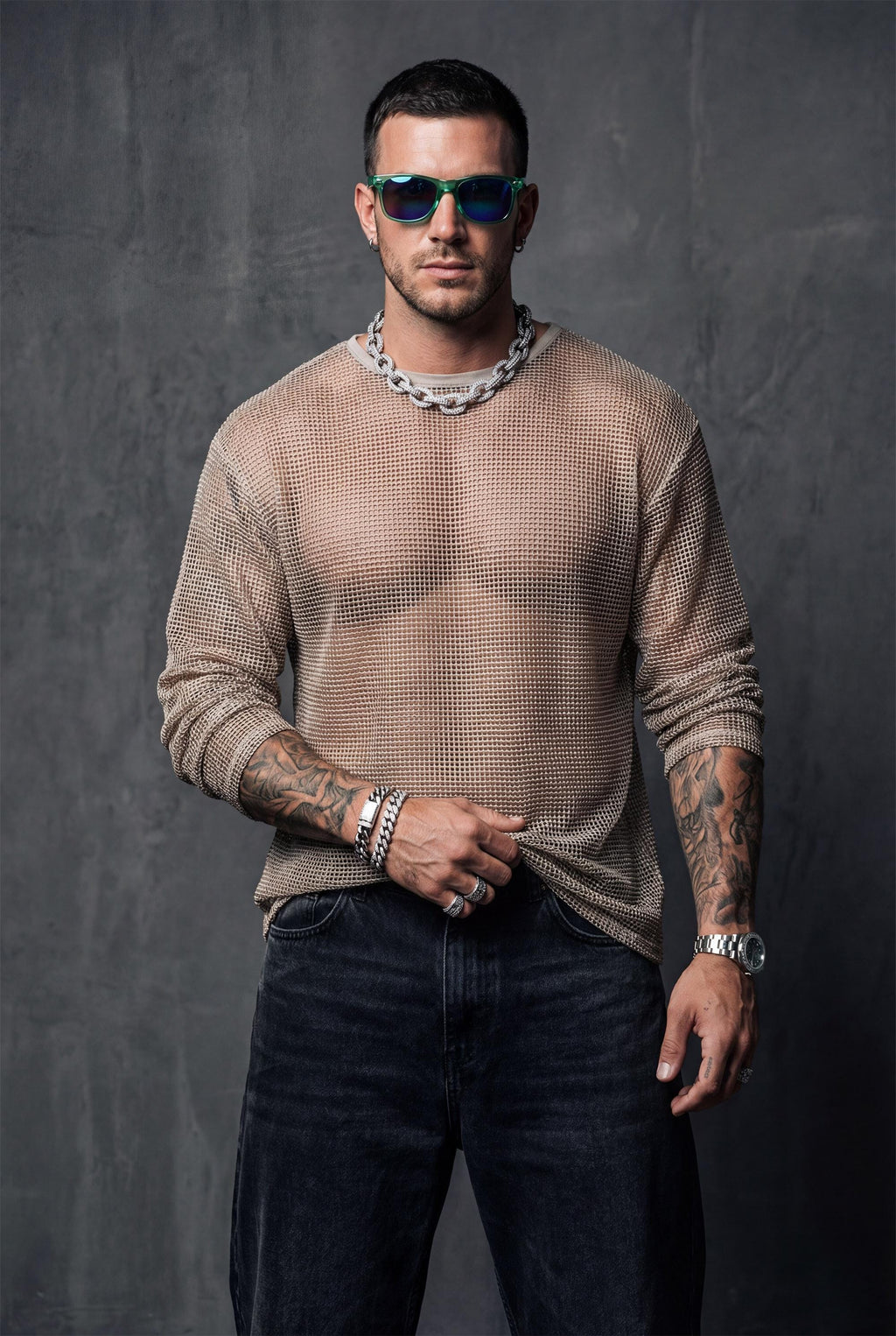 Beige sheer mesh top by PIEL worn from the front by a man. Unisex transparent mesh shirt with fluid straight cut, lightweight breathable fabric revealing the body. Festival wear, clubwear, rave outfit, beachwear, queer fashion, modern minimal unisex clothing.