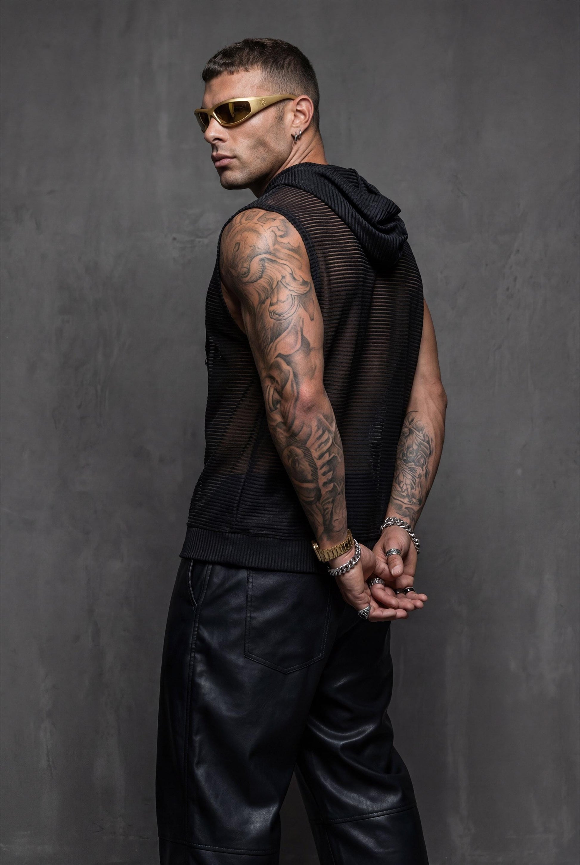 Black transparent hooded tank right side view showing loose fit and semi-sheer mesh with subtle shimmer. Essential rave wear for men seeking bold festival outfits and pride clothing. This sleeveless mesh top provides breathable comfort perfect for dancing, beach parties, or summer streetwear. Hooded design adds urban edge to gay fashion and queer style for confident self-expression at clubs or outdoor events.