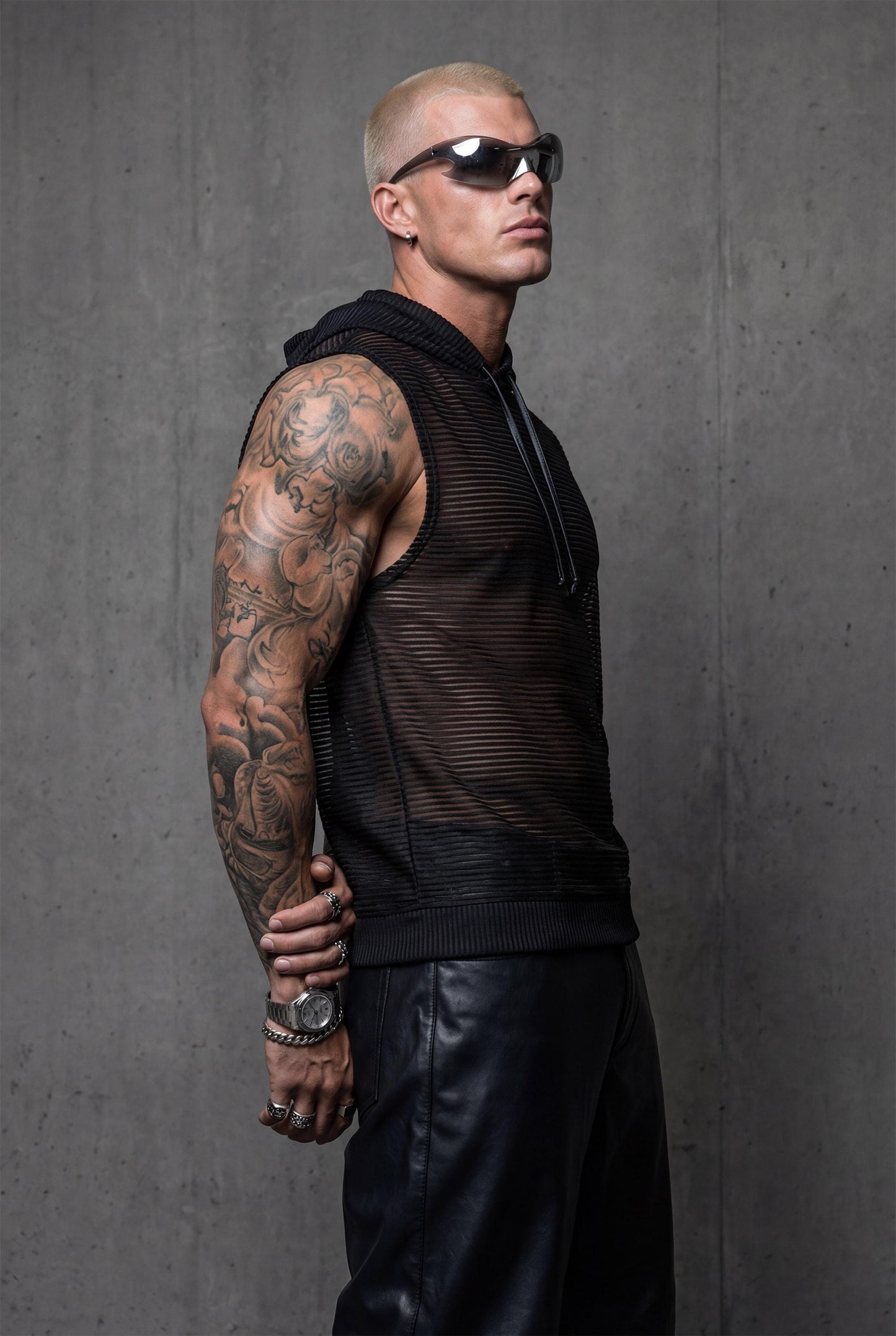 Black transparent hooded tank right side view showing loose fit and semi-sheer mesh with subtle shimmer. Essential rave wear for men seeking bold festival outfits and pride clothing. This sleeveless mesh top provides breathable comfort perfect for dancing, beach parties, or summer streetwear. Hooded design adds urban edge to gay fashion and queer style for confident self-expression at clubs or outdoor events.