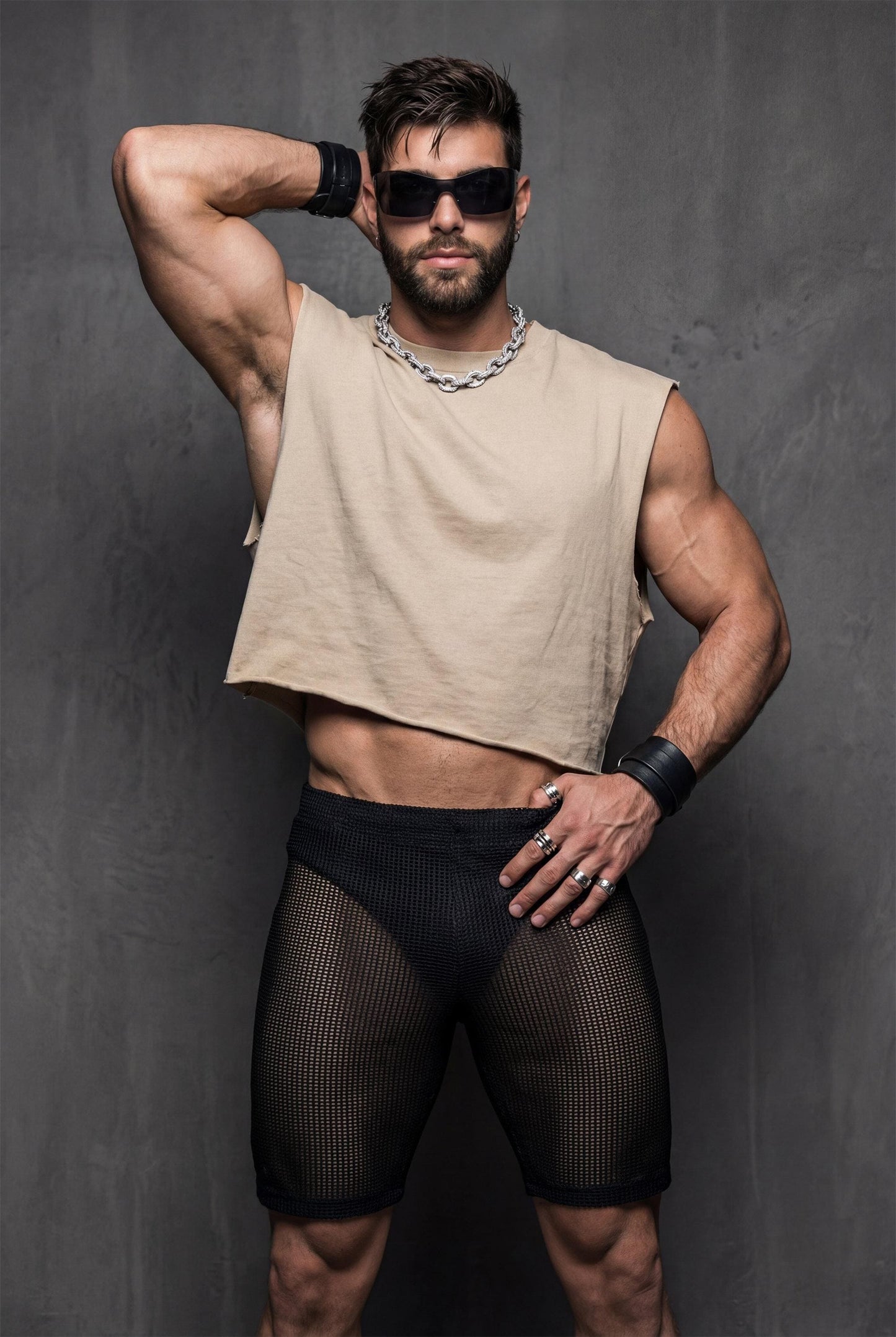 Front view of black transparent mesh shorts worn by a muscular man. Sheer fabric reveals the body underneath while keeping a fitted, athletic cut. Designed for gay club wear, Berlin nightlife, circuit parties, and pride events. Sexy, breathable party shorts for men who want bold, confident, and eye-catching club outfits.