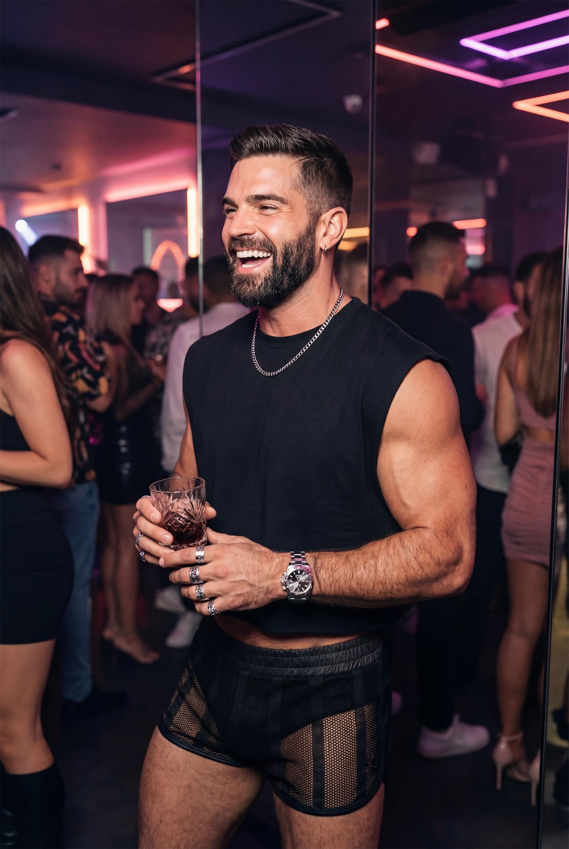 Muscular bearded man wearing black sheer mesh shorts and a sleeveless black top, standing in a nightclub with neon lights and a blurred crowd in the background. He holds a drink and smiles confidently, showcasing transparent mesh fabric, athletic legs, and a bold clubwear look. Gay men’s party outfit designed for nightlife, circuit parties, queer events, and club fashion with a strong masculine attitude.