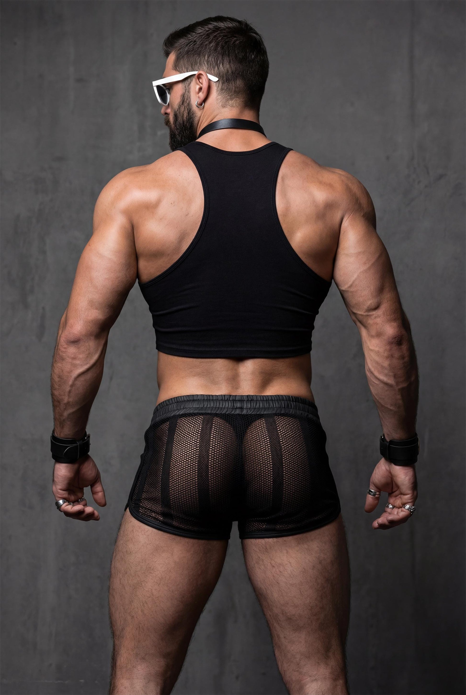 Back view of black sheer mesh shorts men with transparent fabric and snug fit. Men’s festival shorts designed for pride events, circuit parties and gay clubwear, revealing silhouette with faux leather waistband and short cut.