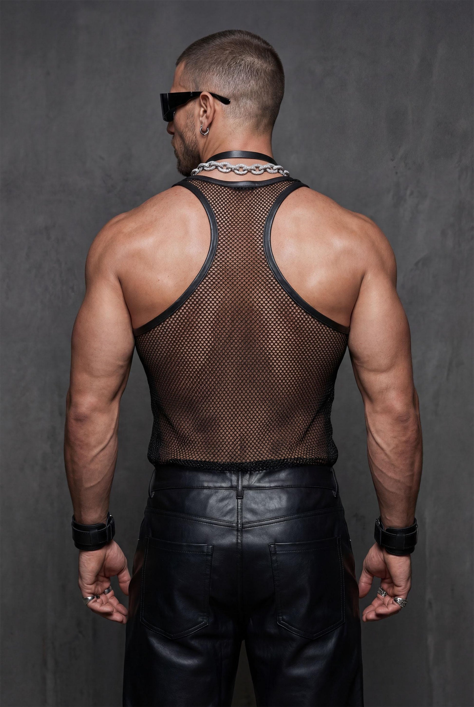 Black transparent mesh tank top front view under open jacket showcasing racerback stringer for layered gay fashion statements. See-through athletic top reveals body confidence while maintaining versatile style from street to club. Perfect LGBTQ+ pride outfit combining provocative mesh construction with sophisticated layering for circuit parties, rave festivals, or urban nightlife scenes. Breathable nylon fabric ideal for confident queer fashion lovers embracing bold alternative style.