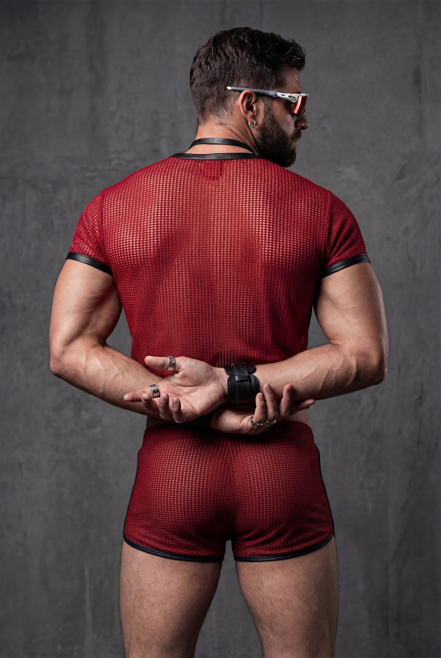 Back view red transparent mesh crop top and see-through shorts displaying full sheer construction and cropped athletic silhouette - PIEL statement menswear for gay circuit parties rave festivals - breathable polyester mesh fabric shows body confidence masculine energy - queer fashion designed for techno clubs pride events underground parties burning man - bold red outfit perfect for festival season beach raves lgbtq celebrations fetish wear