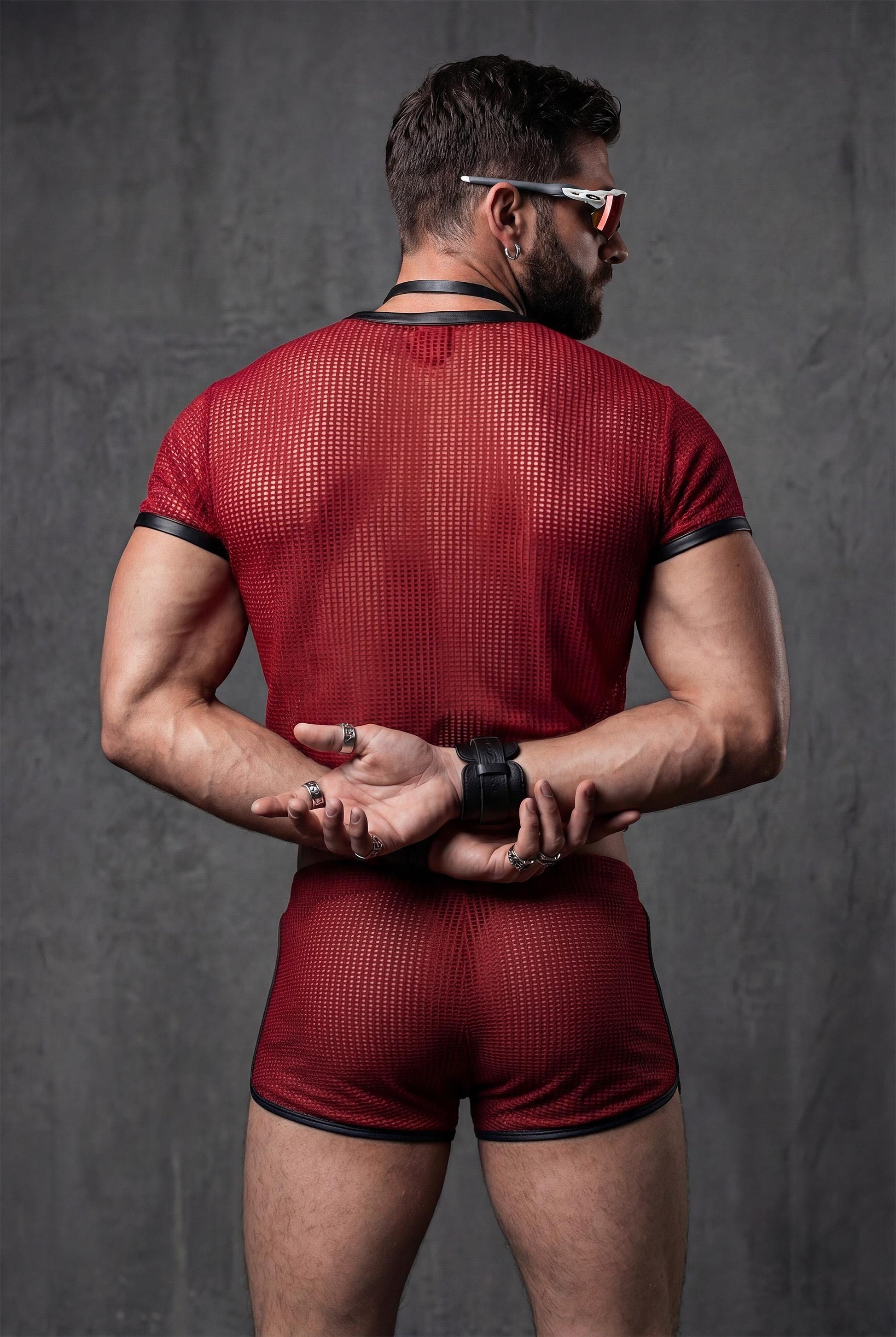 Back view red transparent mesh crop top and see-through shorts displaying full sheer construction and cropped athletic silhouette - PIEL statement menswear for gay circuit parties rave festivals - breathable polyester mesh fabric shows body confidence masculine energy - queer fashion designed for techno clubs pride events underground parties burning man - bold red outfit perfect for festival season beach raves lgbtq celebrations fetish wear