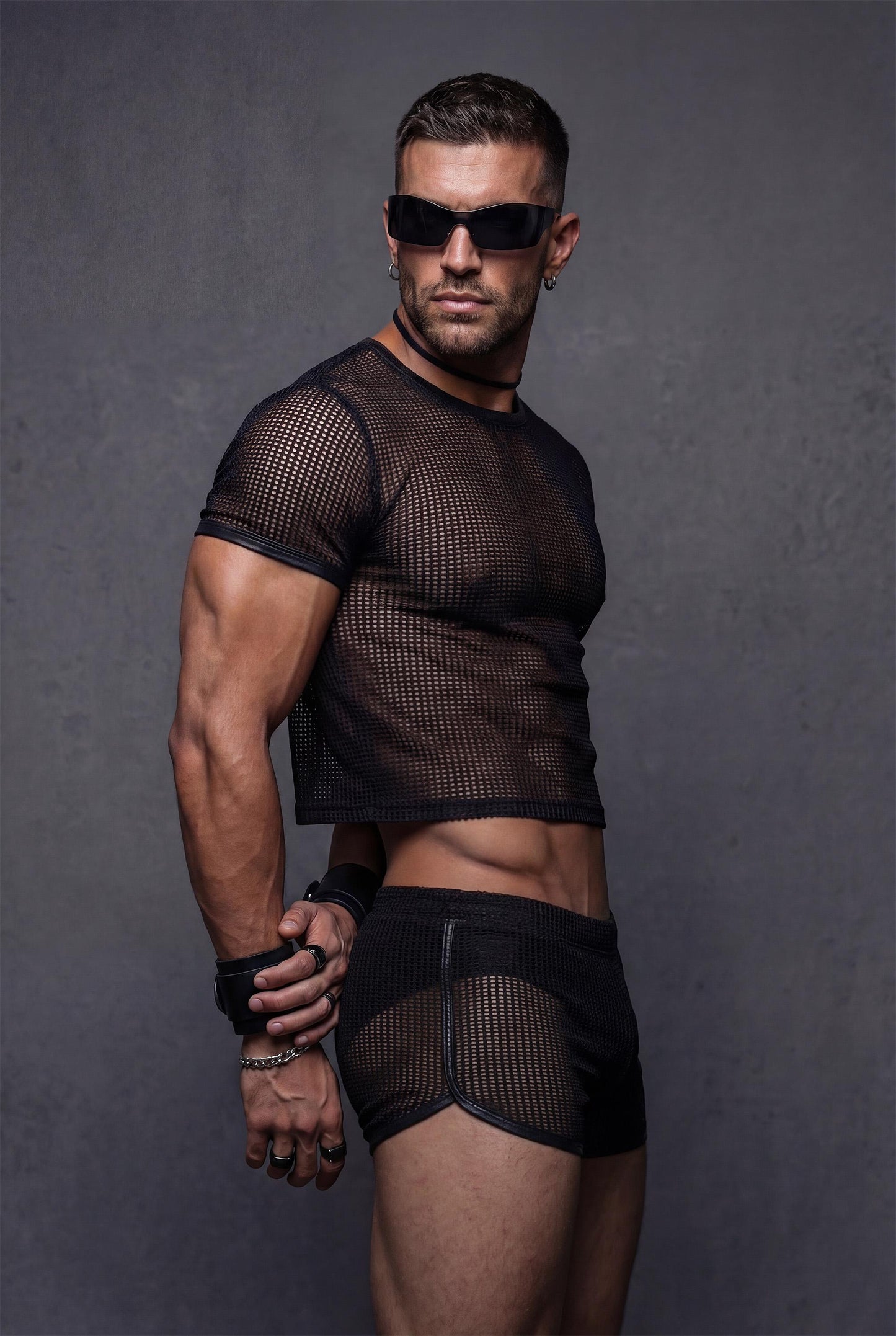 Side profile view black transparent mesh crop top with vegan faux leather contrast trim paired with see-through shorts - PIEL Night Starter bundle for gay circuit parties rave festivals - athletic body-hugging fit shows masculine physique - queer fashion statement piece for techno clubs underground parties pride celebrations burning man outfits - breathable sheer fabric designed for dancing all night