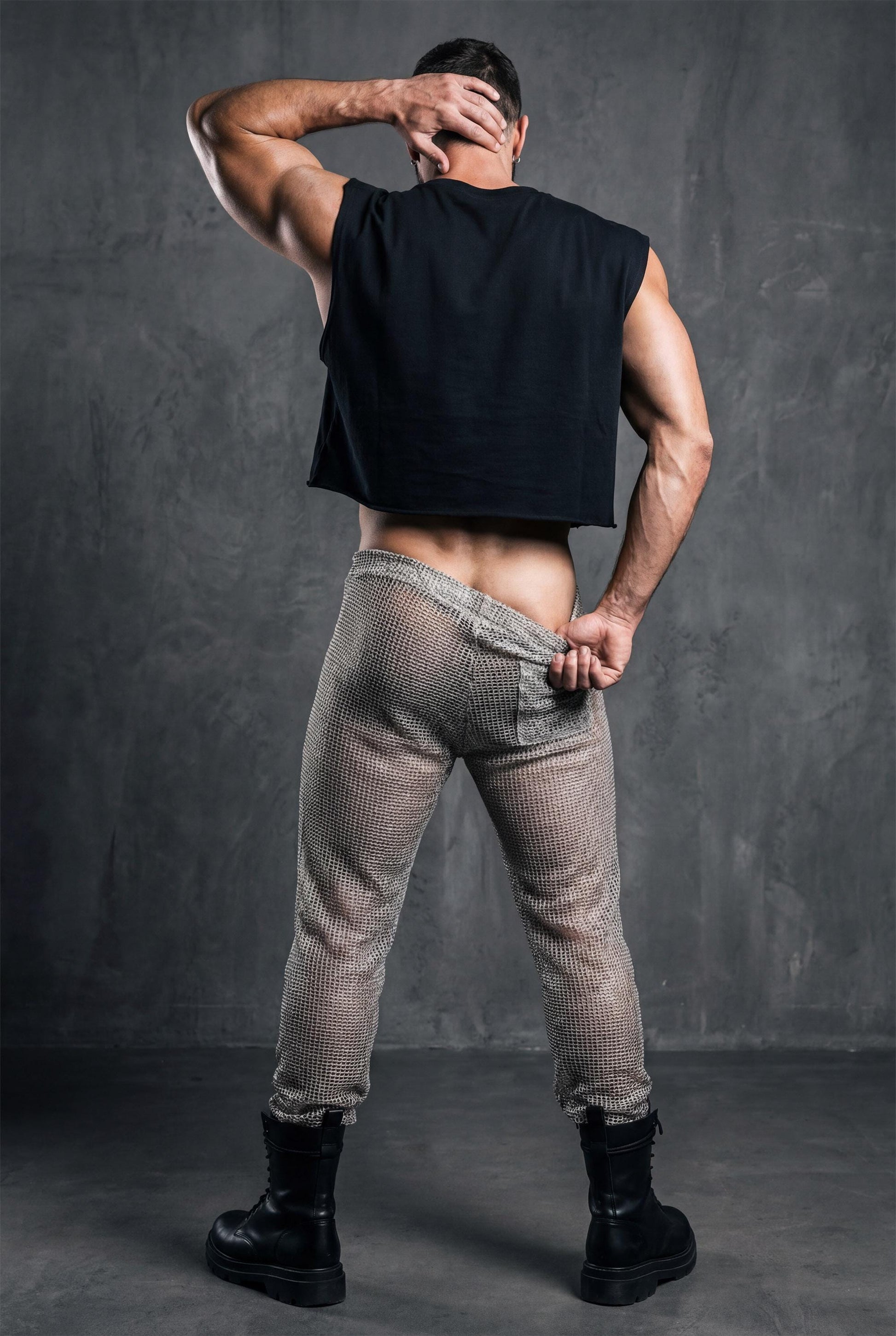 Beige see-through knit mesh jogger pants. Open-knit texture creates breathable airy feel while revealing skin beneath. Ideal for Burning Man, beach parties, pride festivals, and circuit party style. Shows versatility of matching separates. Essential coordinated look for men embracing bold transparent aesthetic with confident self-expression and unique festival fashion sense.