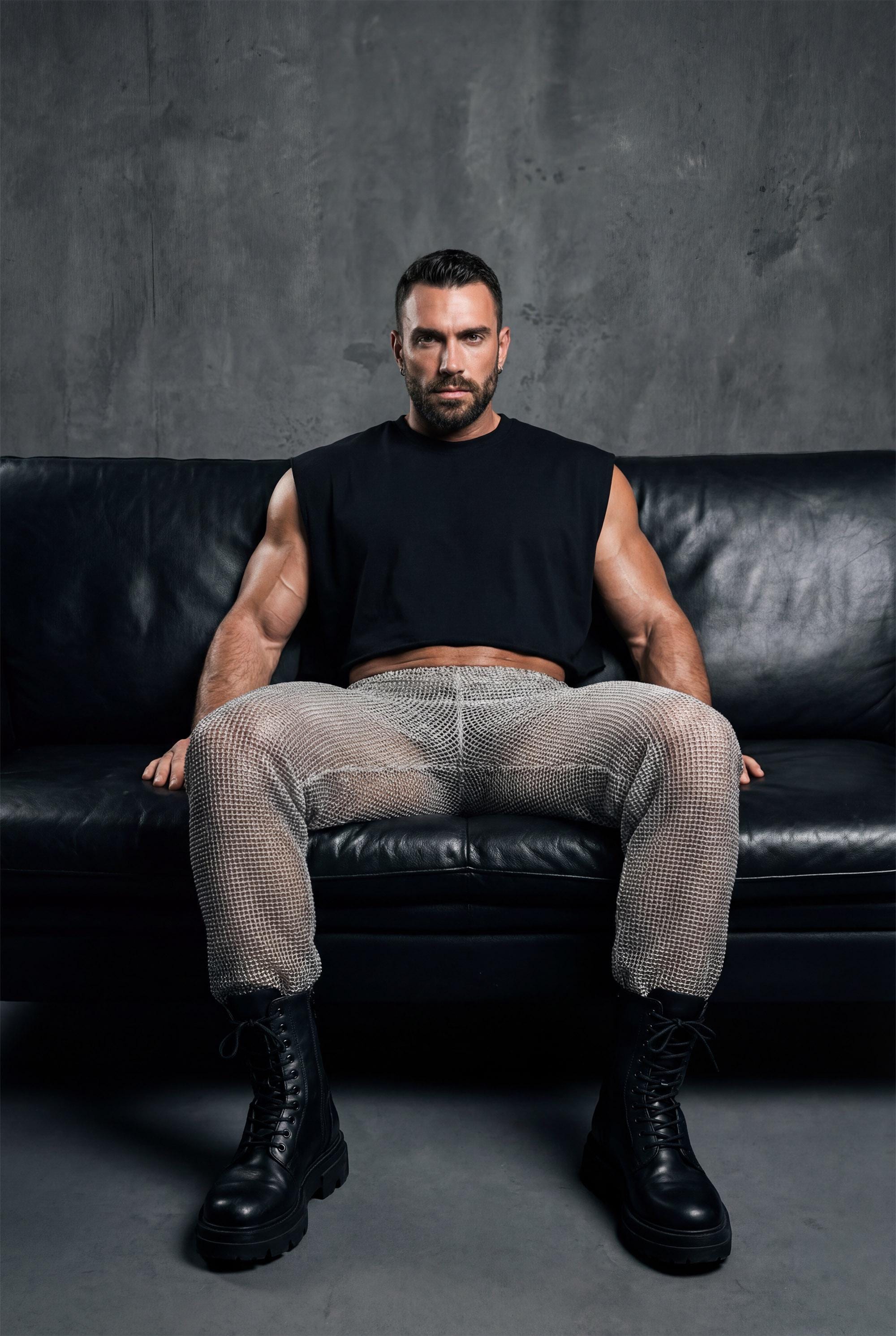 Beige see-through knit mesh jogger pants men with elastic cuffs and drawstring waist, perfect for gay casual wear, rave festival outfit, and relaxed summer style. Breathable open-knit fabric offers ventilation while creating unique textured look. Available in beige and black. Ideal for beach parties, festival lounging, pride events, and casual clubwear. Elastic waistband ensures comfort. Statement piece for men who embrace bold transparent fashion with laid-back confidence and individuality.